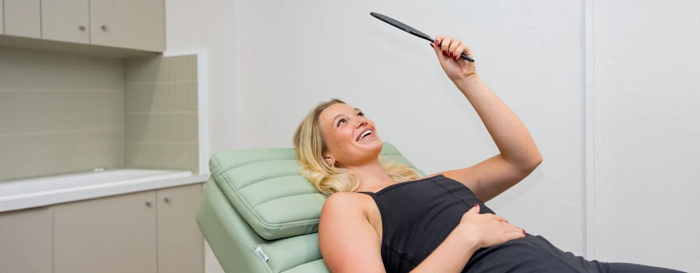 Woman holding a mirror on a mint treatment chair